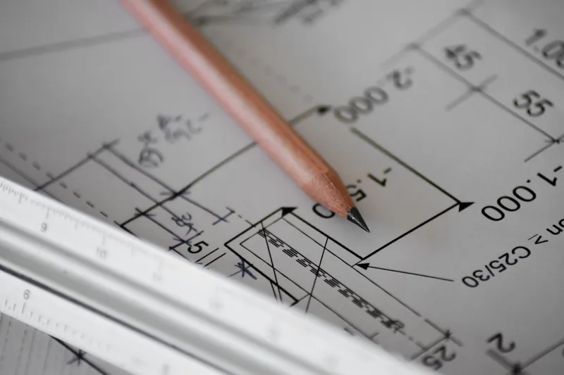 Bouwplan met maatvoering, potlood en rolmeter op de tekentafel