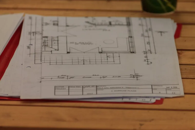 Bouwplannen van een renovatie uitgespreid op een houten tafel